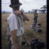 Sean Morris, pointing at something with Mark MacEwen and his guns in the background. 'Wild Ladies of Viramba', 2002